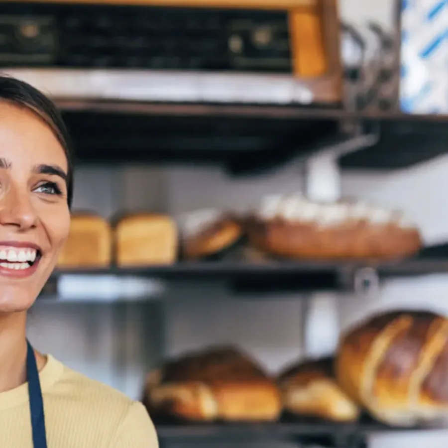Smiling bakery assistant behind the shop counter